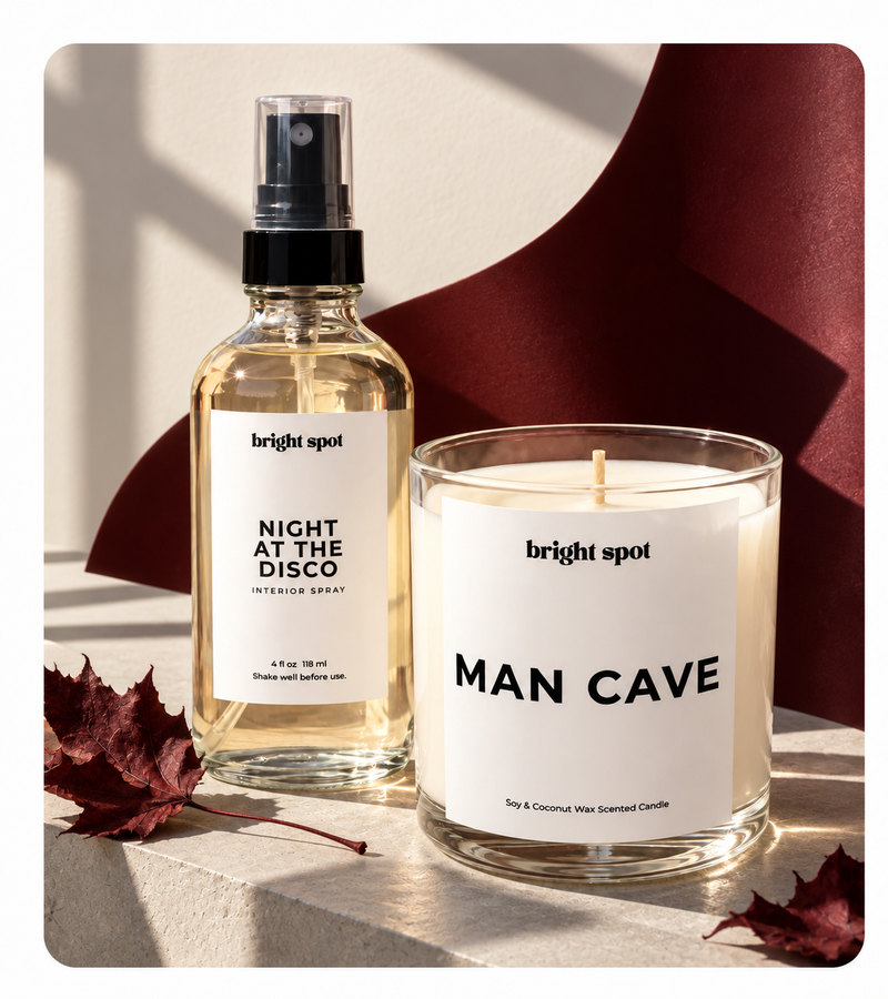 Bright Spot home fragrance set featuring a 'Night At The Disco' interior spray bottle and a 'Man Cave' soy & coconut wax scented candle, styled with autumn leaves on a stone surface.